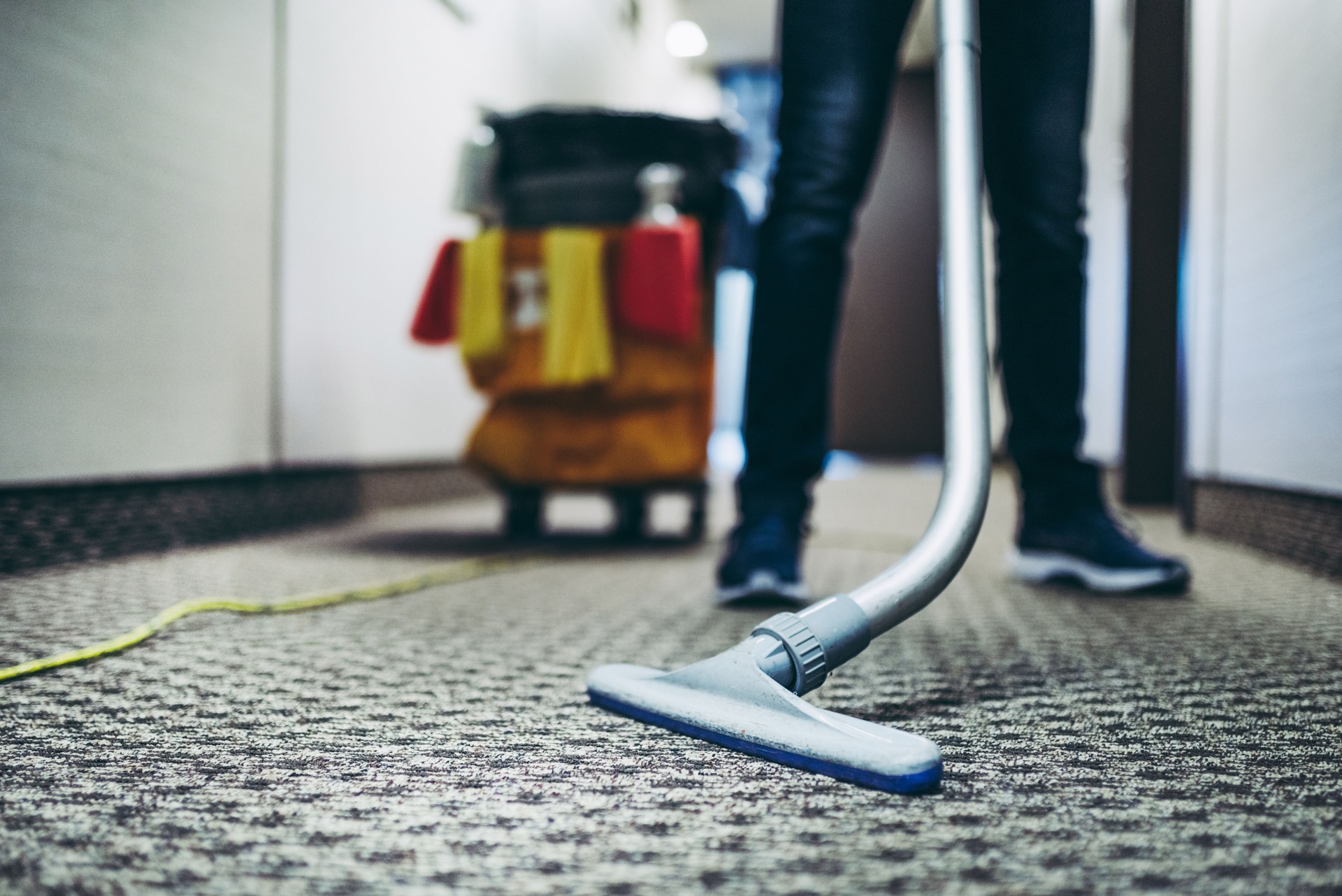 Janitor vacuum cleaning the corridor of an office building.