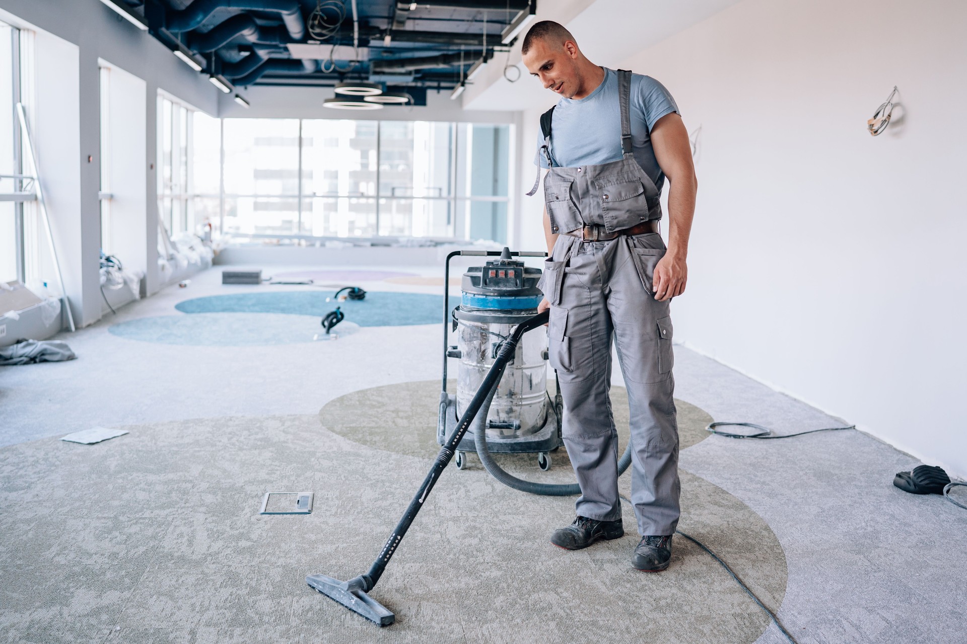 Young man meticulously vacuums the carpet after installation