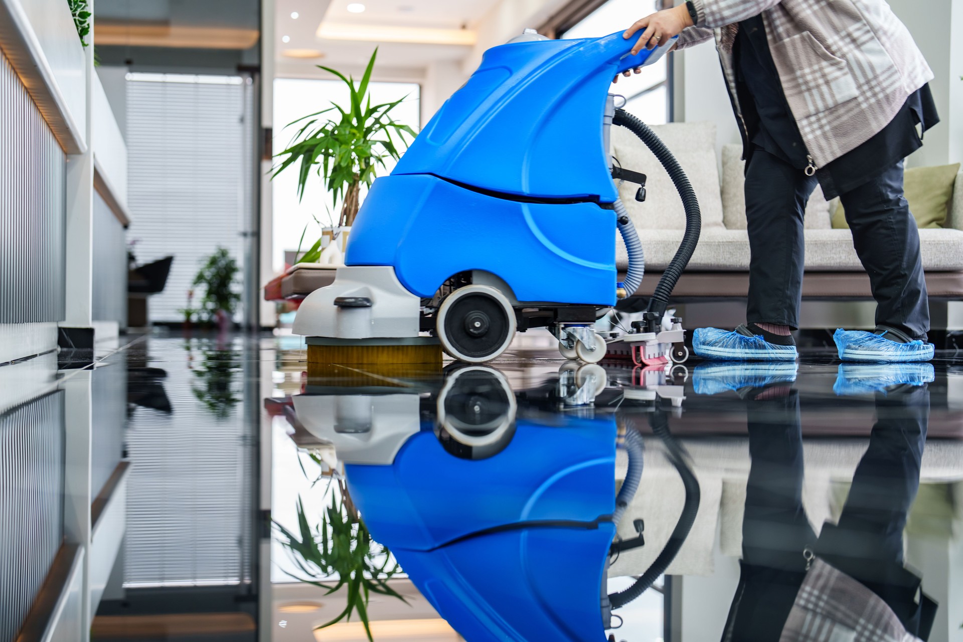 Female worker cleaning office lobby floor with machine